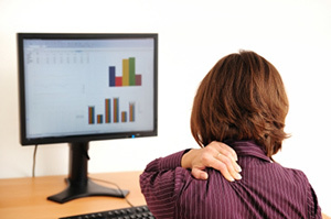 Zervikale Osteochondrose in einer Frau, die an einem Computer sitzt